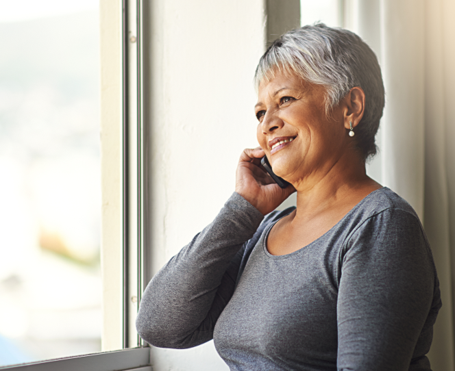 Grey haired woman smiling while on the phone with a call center representative 