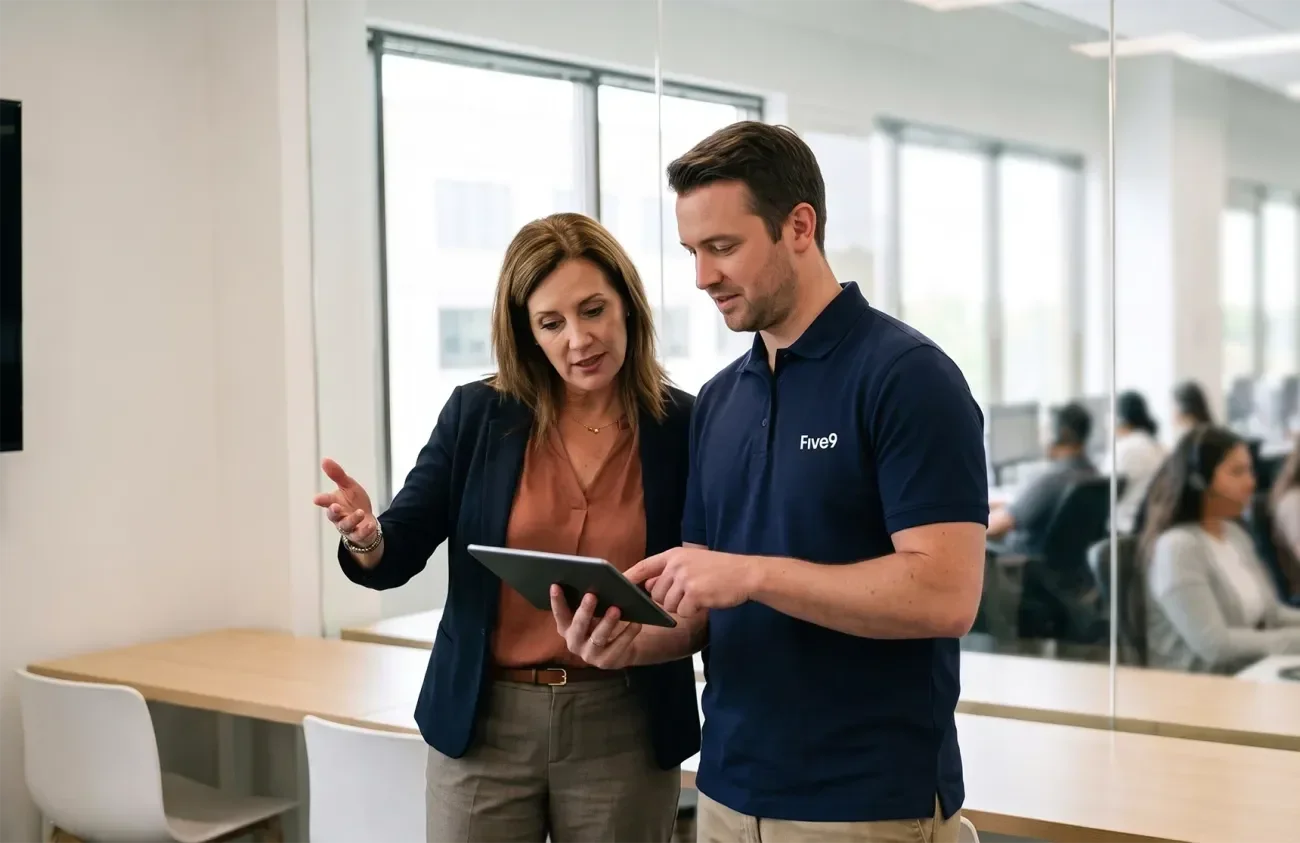 A woman and a man discuss a tablet in a modern office setting.