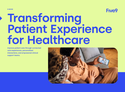 A woman sits on a couch, looking at her phone while another woman leans in, engaged.