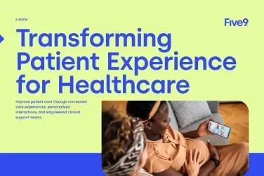 A woman sits on a couch, looking at her phone while another woman leans in, engaged.