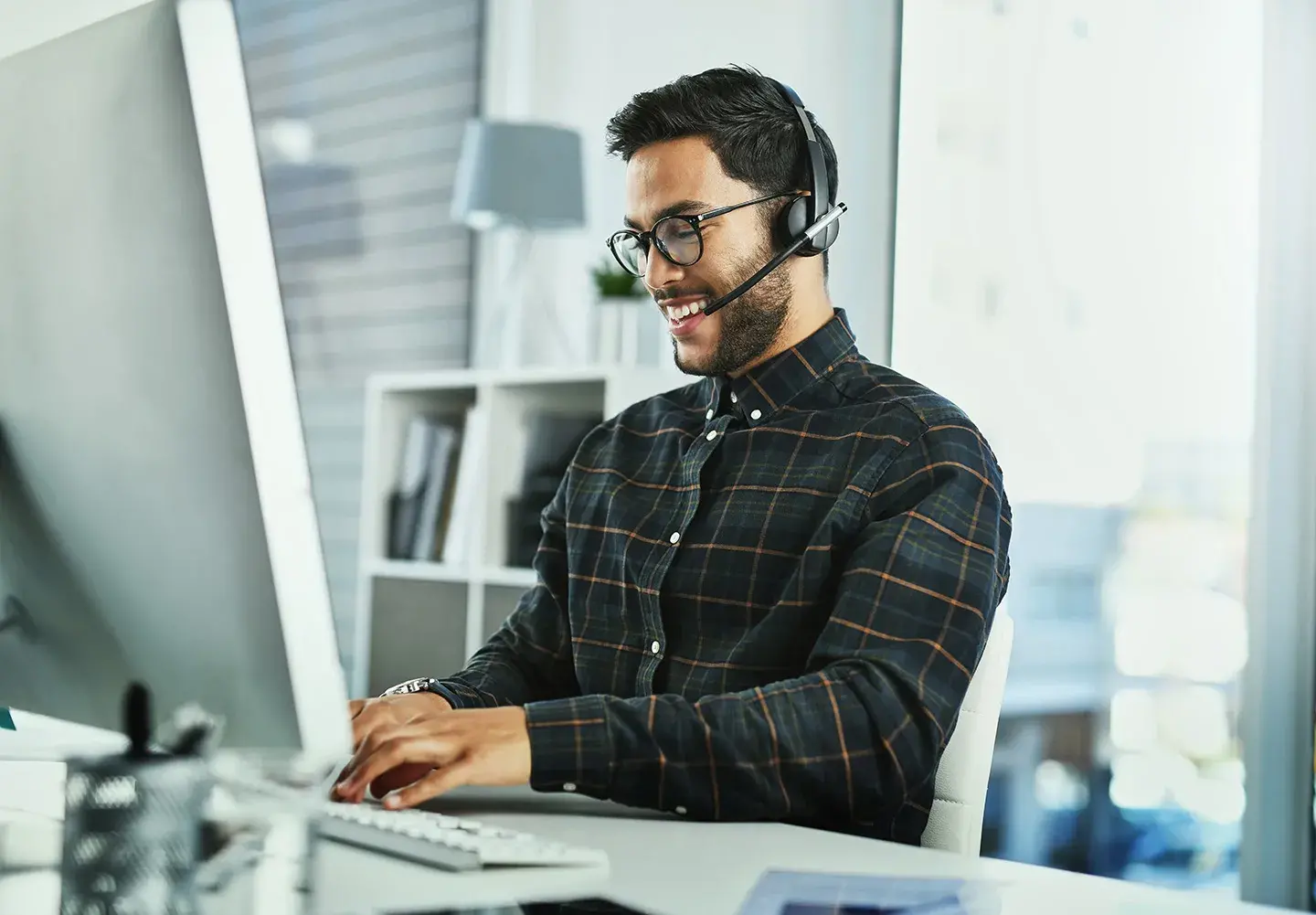 Customer service representative at his desk talking on a headset to a customer