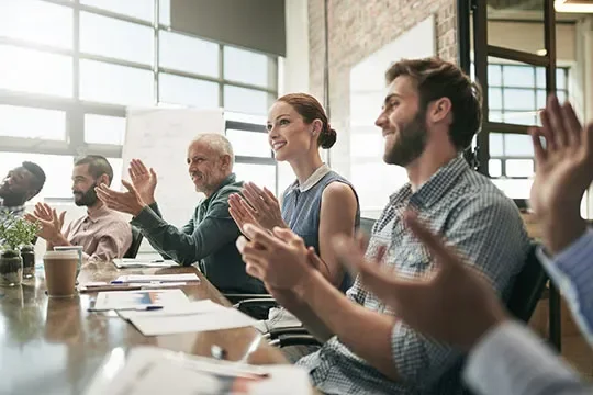 A group of people clapping around a desk