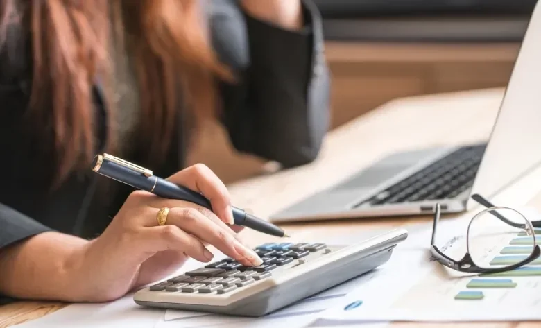 Woman typing on a calculator at a desk