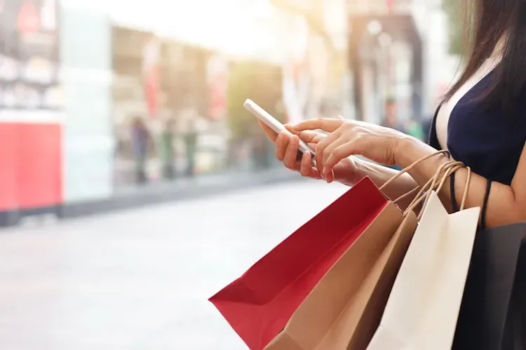 Woman holding shopping bags and a phone