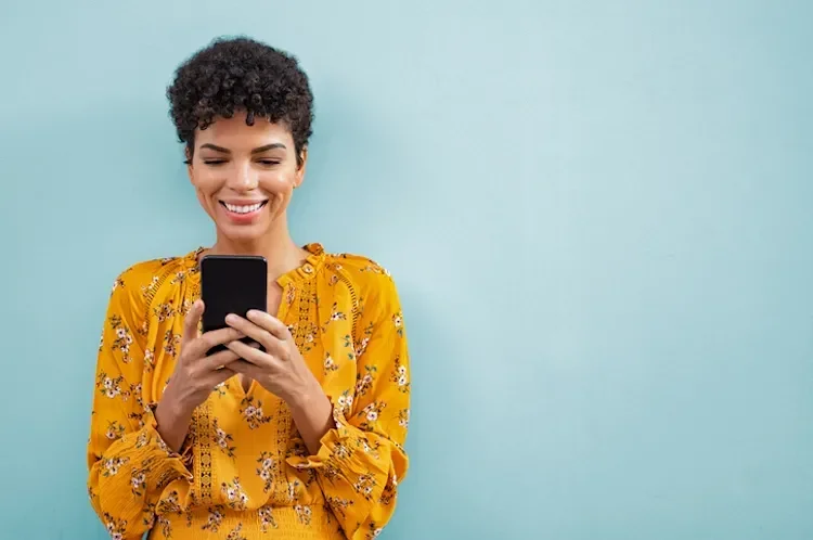 Woman on a blue background smiling at her mobile phone