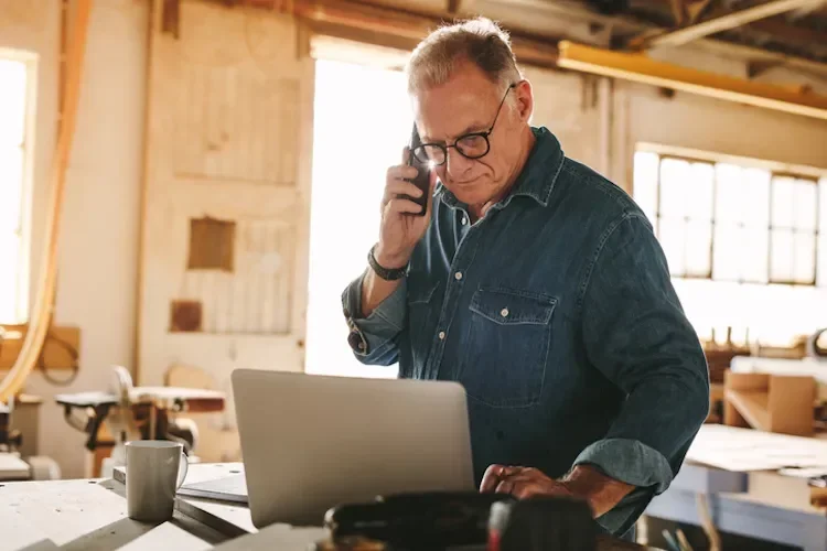 Man on a call while looking at a laptop in his home
