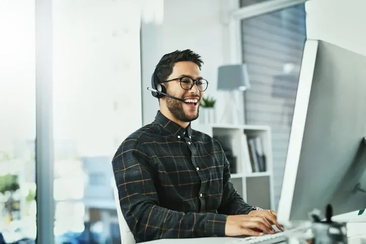 Man with headset smiling at computer