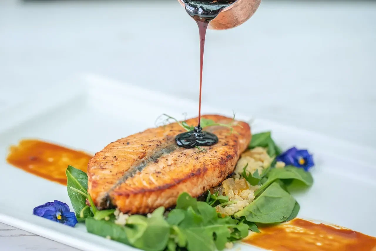 Sauce being poured onto a salmon dish