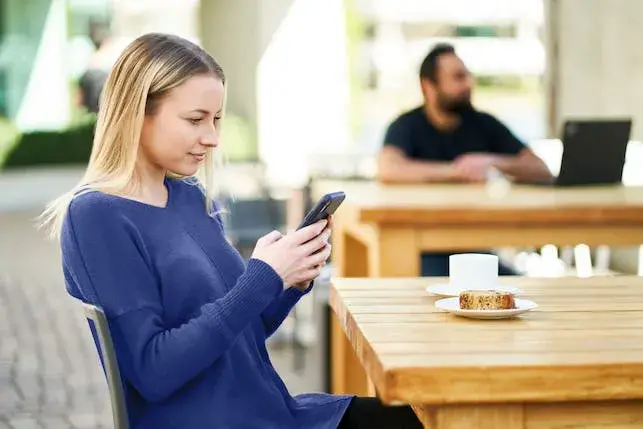 Girl looking at phone while drinking coffee