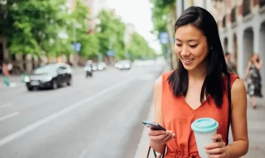 Woman Using Phone on Sidewalk