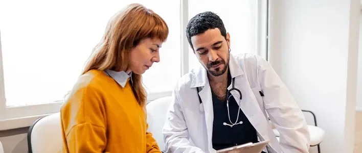 A doctor and a patient review information together in a bright, modern office.
