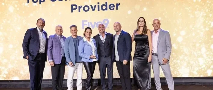 Group posing together on stage in formal attire, celebrating Five9 winning the Sandler Summit award.