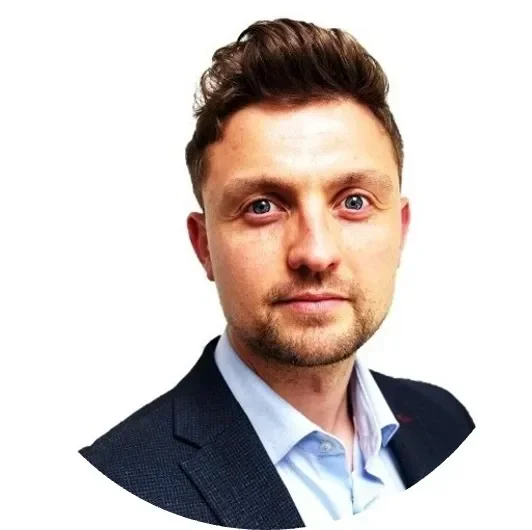 Headshot of a man with short, curly hair, wearing a suit and looking directly at the camera.