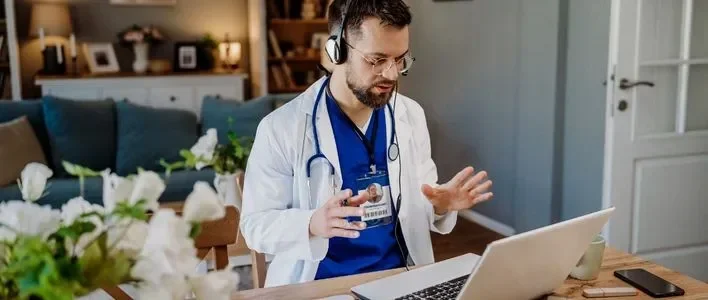 Healthcare professional in a white coat engaging in telemedicine at home.