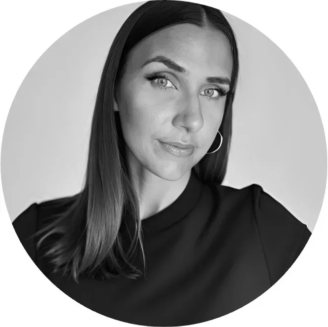 Black and white portrait of a woman with long hair, wearing a dark top, looking confidently at the camera.