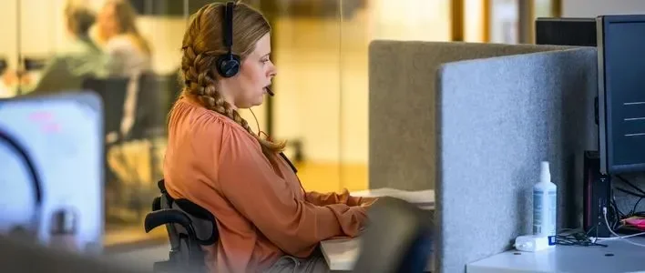 A woman with headphones focused on her work in a modern office setting.