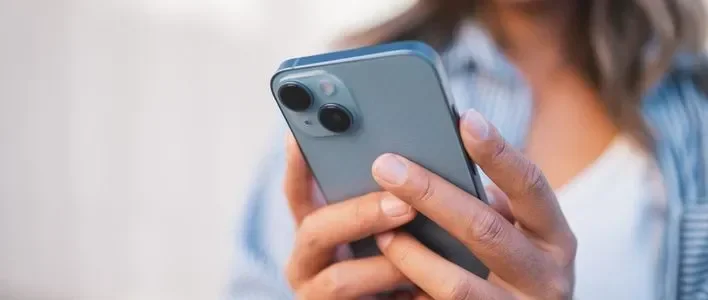 A person holding a smartphone with a gray case, focused on the screen.