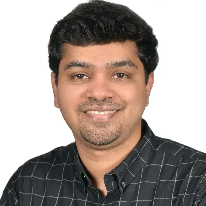 Smiling man wearing a black checkered shirt against a plain background.