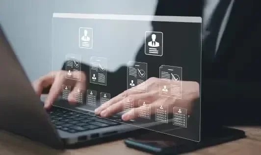 Hands typing on a laptop with virtual icons and data overlay.