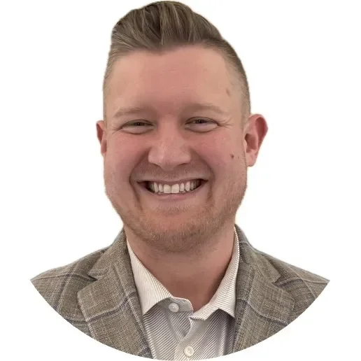 Smiling man in a light gray blazer with a plaid pattern, set against a white background.