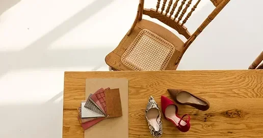Wooden table displaying color swatches and two pairs of shoes beside a cane-backed chair.