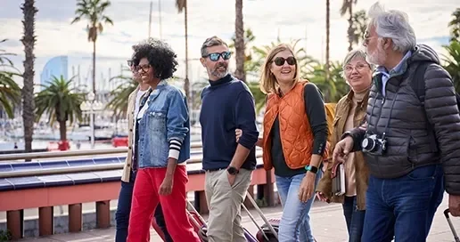 A diverse group of five people walking together along a waterfront promenade, smiling.