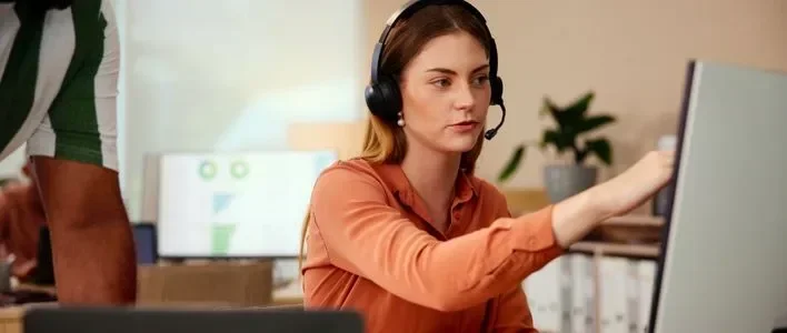 Woman wearing orange shirt pointing at computer screen