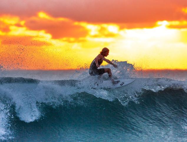 Surfer on wave at sunset 