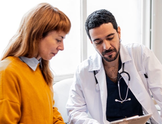 A doctor and a patient review information together in a bright, modern office.