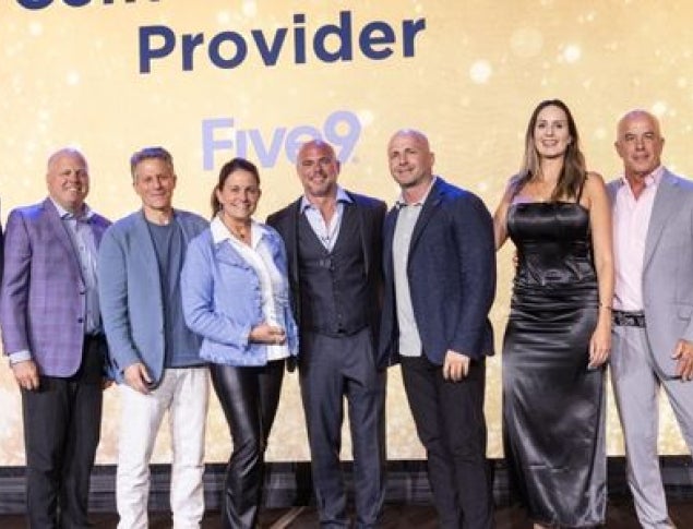 Group posing together on stage in formal attire, celebrating Five9 winning the Sandler Summit award.