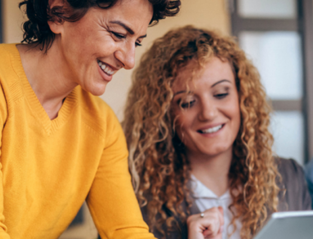 Three cheerful people collaboratively looking at a tablet in a bright, modern setting.