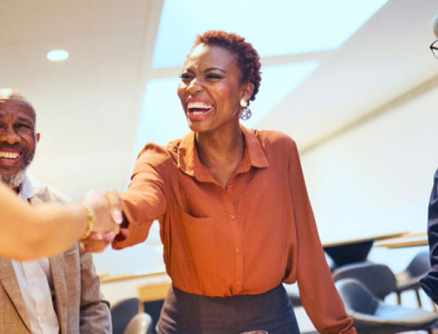 A group of four Five9 partners engaging in a welcoming handshake indoors.