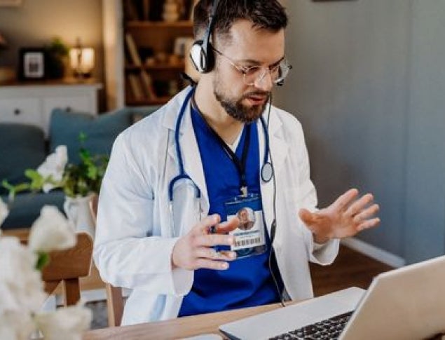 Healthcare professional in a white coat engaging in telemedicine at home.