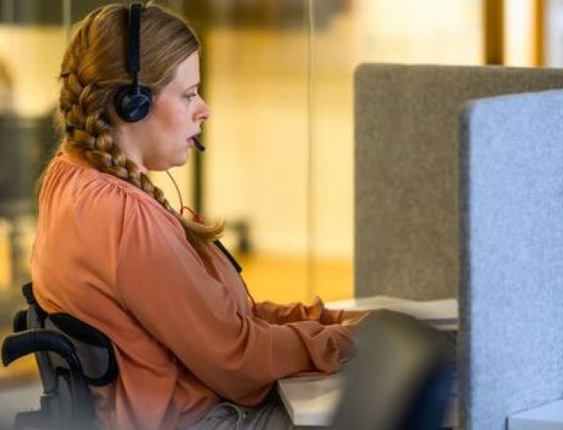 A woman with headphones focused on her work in a modern office setting.