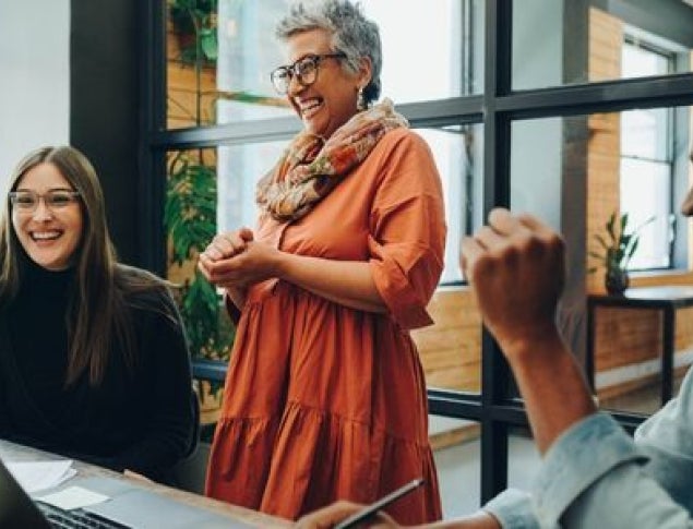 Group of people in a bright office, engaged in a joyful conversation and collaboration.