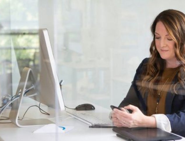 A woman with long brown hair sits at a desk, holding a pen and looking thoughtfully at her notes.